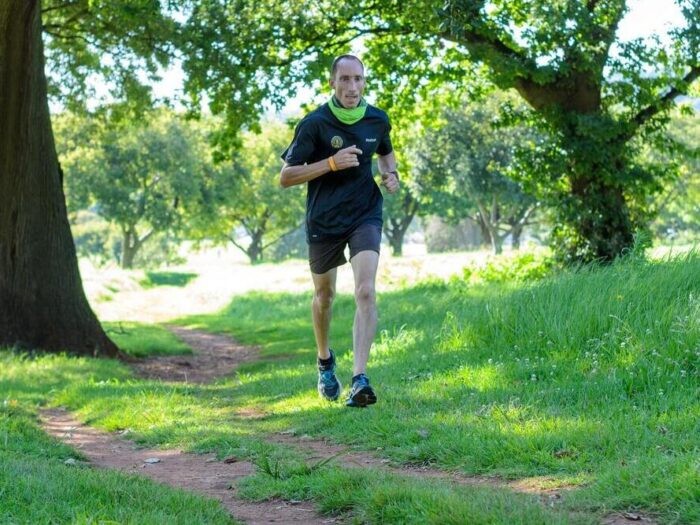 mężczyzna biegnący wśród drzew w stroju sportowym